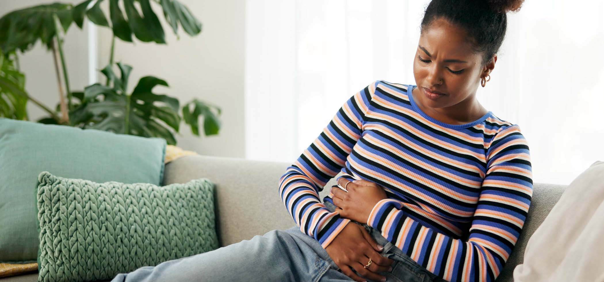 cramps-pain-and-woman-in-lounge-home-and-reactio-2025-04-06-11-04-49-utc (1)