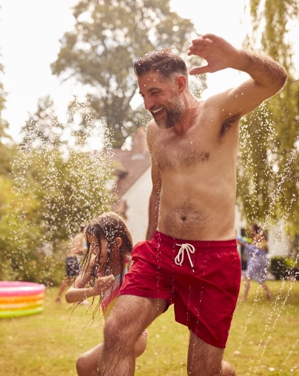 father-and-daughter-run-through-water-from-garden-2024-10-19-10-54-55-utc